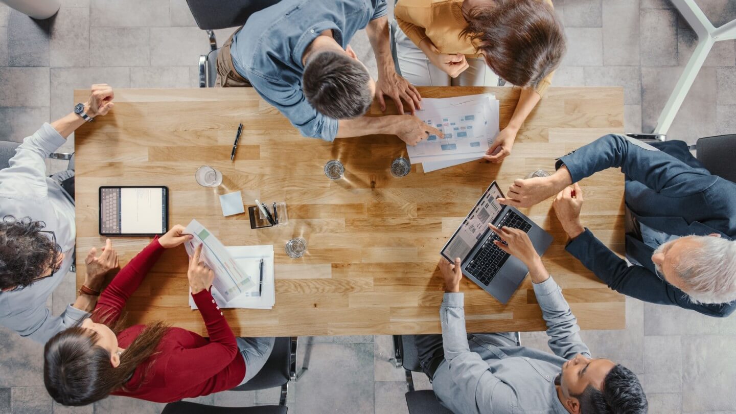Mitarbeiter sitzen zusammen an einem Tisch und arbeiten.