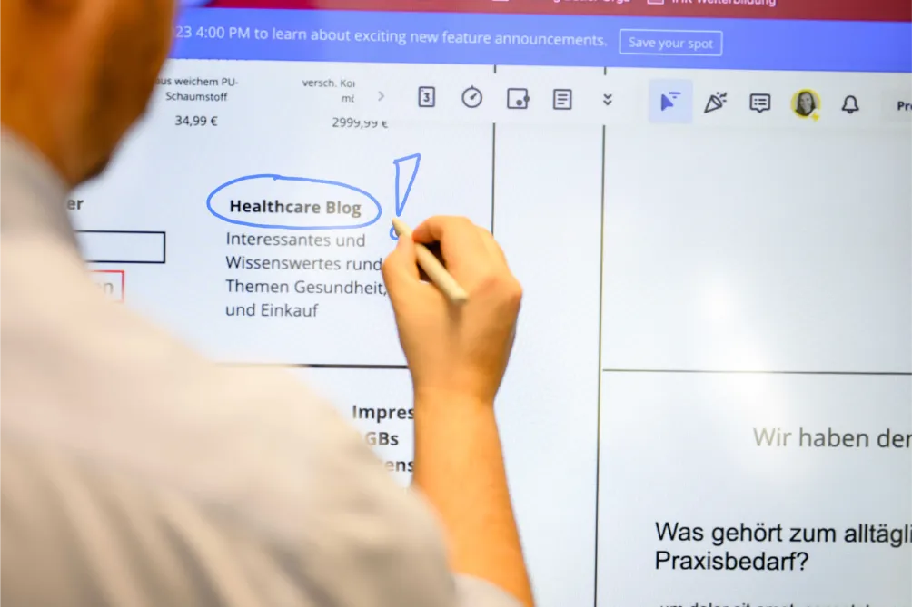Person markiert „Healthcare Blog“ auf digitalem Whiteboard mit deutscher Website während einer SEO-Konzept-Brainstorming-Sitzung.