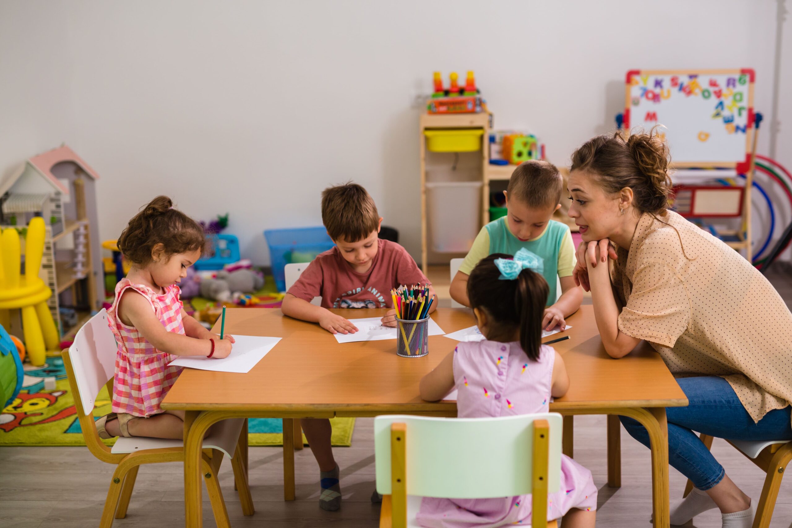 Lehrerin mit vier Kindern, die im Rahmen eines Pro-Bono-Projekts in einem Spielzeug-Klassenraum malen.